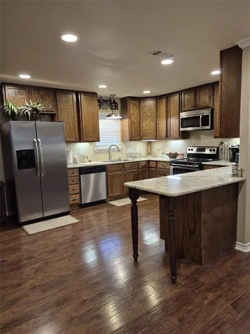 a kitchen with stainless steel appliances granite countertop a table chairs sink refrigerator and microwave