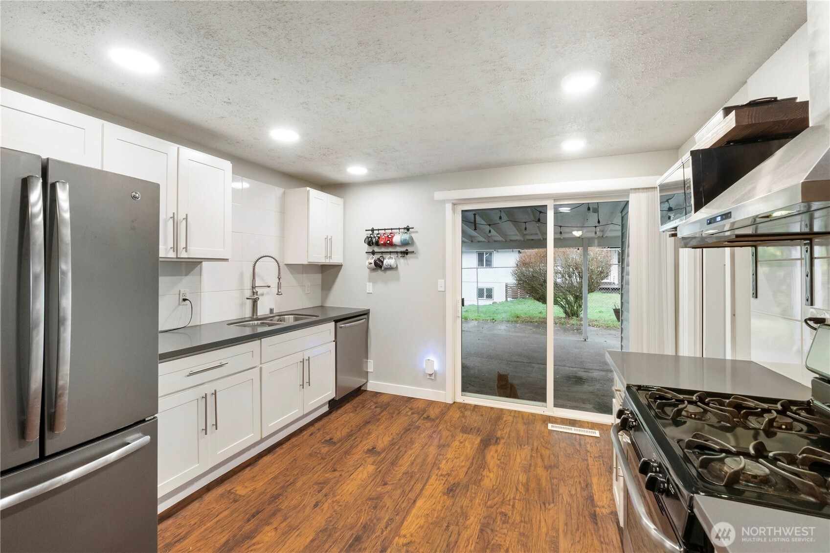 2322 Pamela Place Steilacoom, WA 98388 - Photo 7 of 24 a kitchen with stainless steel appliances granite countertop a refrigerator a sink dishwasher a stove and white countertops with wooden floor
