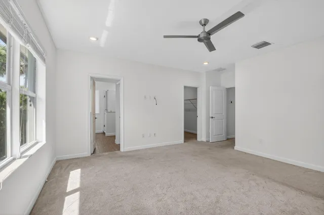 an empty room with ceiling fan and window