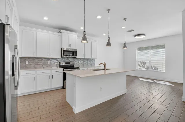 a large kitchen with granite countertop a stove a sink a center island and cabinets