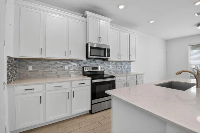 a kitchen with granite countertop white cabinets and stainless steel appliances
