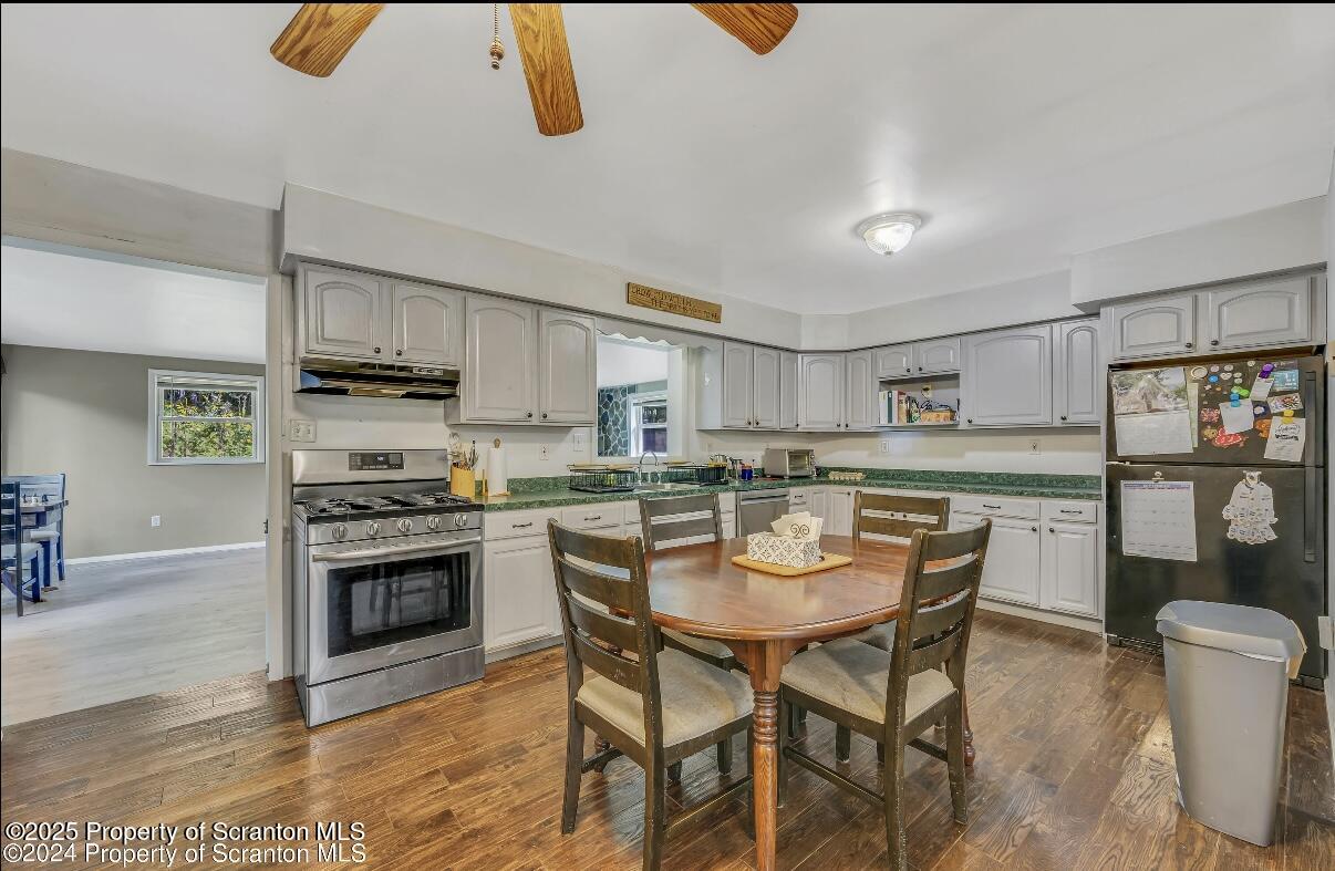 9311 Highway 3004 Springville, PA 18844 - Photo 8 of 51 a kitchen with stainless steel appliances granite countertop a stove a sink dishwasher a dining table and chairs with wooden floor