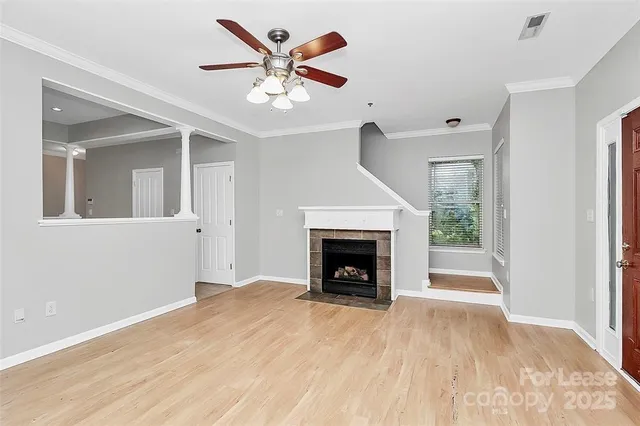 a view of an empty room with wooden floor fireplace and a window