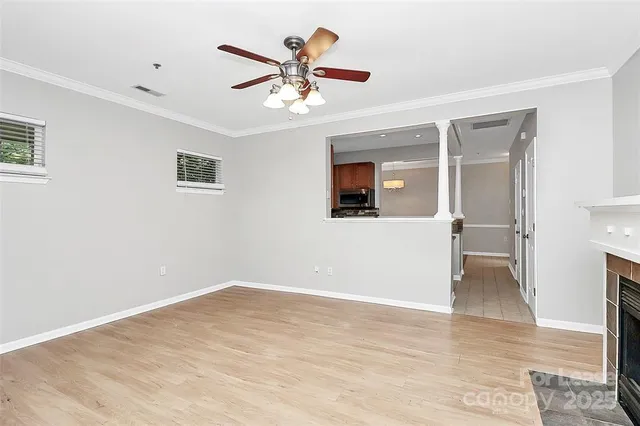 a view of an empty room with wooden floor and a ceiling fan
