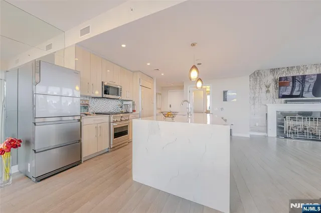 a kitchen with white cabinets stainless steel appliances and wooden floor