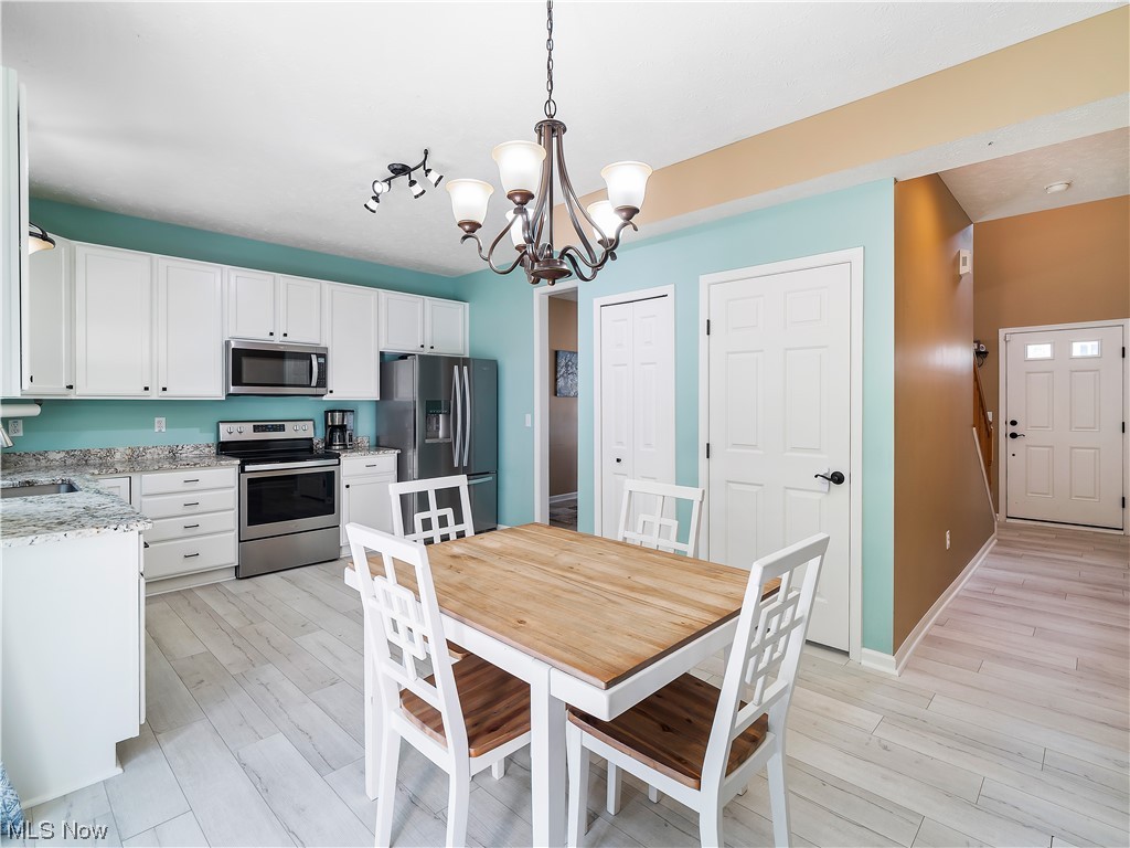 5319 Otten Road North Ridgeville, OH 44039 - Photo 15 of 33 Kitchen with white cabinets, a notable chandelier, light hardwood floors, track lighting, and stainless steel appliances