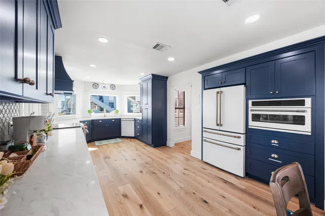 a kitchen with stainless steel appliances kitchen island granite countertop a refrigerator oven a sink dishwasher and wooden cabinets with wooden floor