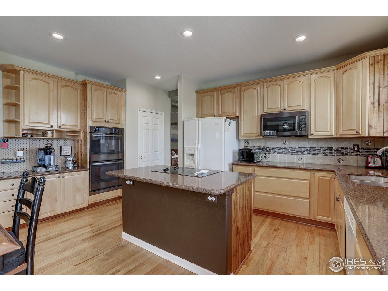 709 Glenarbor Circle Longmont, CO 80504 - Photo 19 of 40 a kitchen with granite countertop a sink a counter top space stainless steel appliances and cabinets