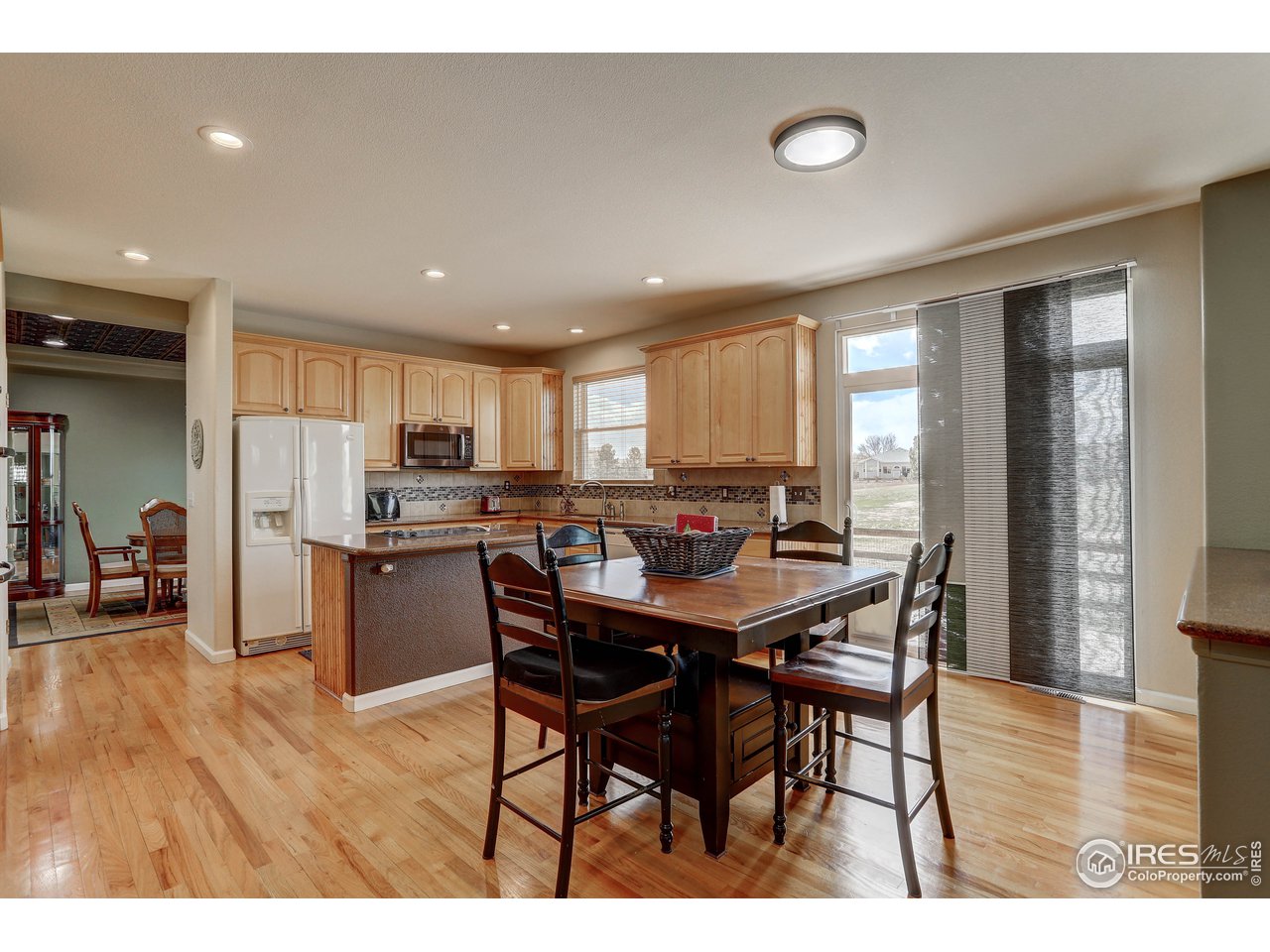 709 Glenarbor Circle Longmont, CO 80504 - Photo 21 of 40 a open dining room with stainless steel appliances kitchen island granite countertop a dining table chairs and a refrigerator