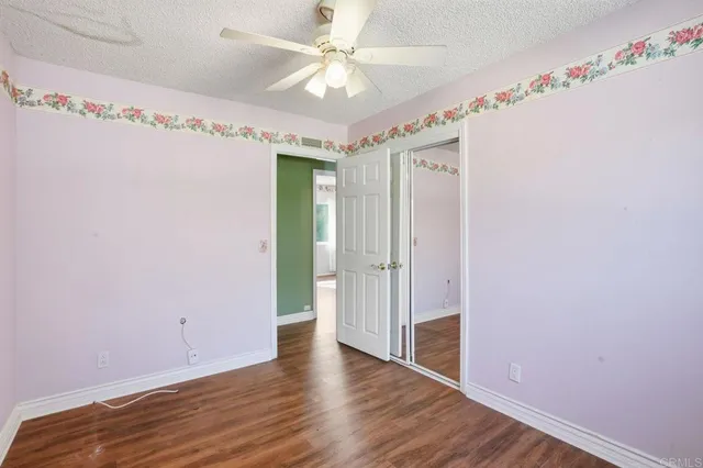 a view of a hallway with wooden floor and a chandelier fan