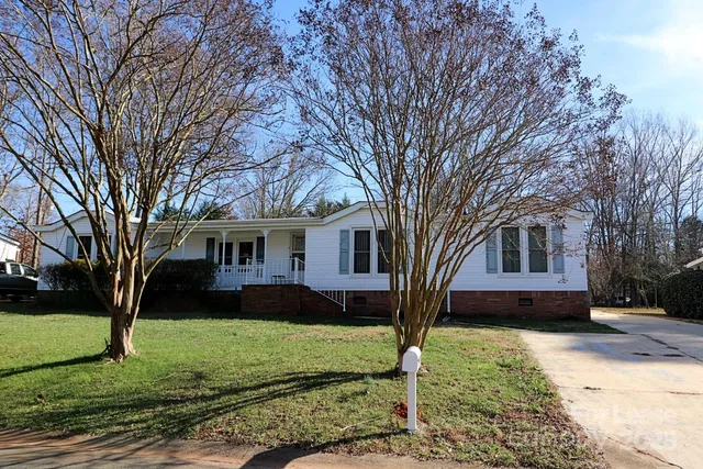 a front view of a house with a garden and trees