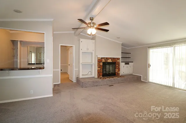 a view of an empty room with window and a kitchen