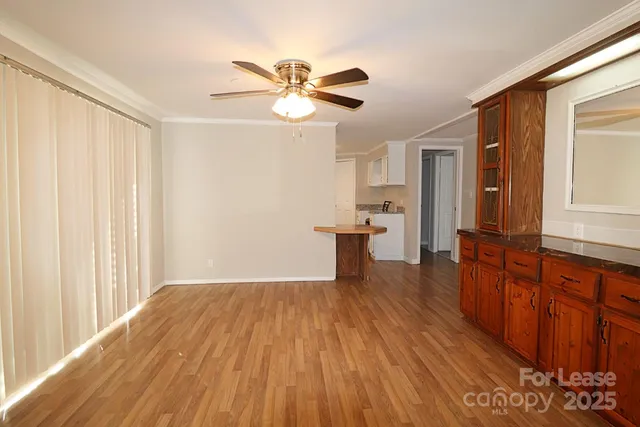 a view of empty room with wooden floor and fan
