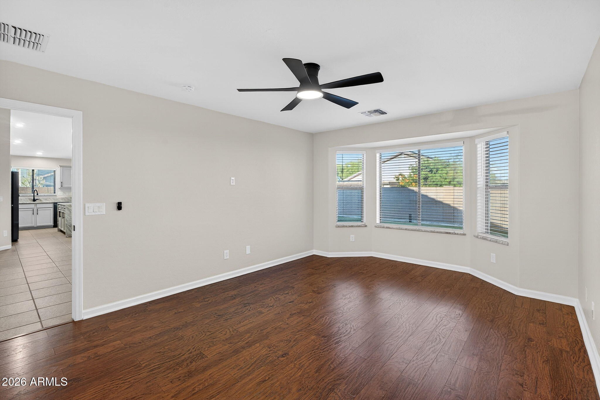 1815 South 174th Avenue Goodyear, AZ 85338 - Photo 31 of 57 an empty room with wooden floor a ceiling fan and windows