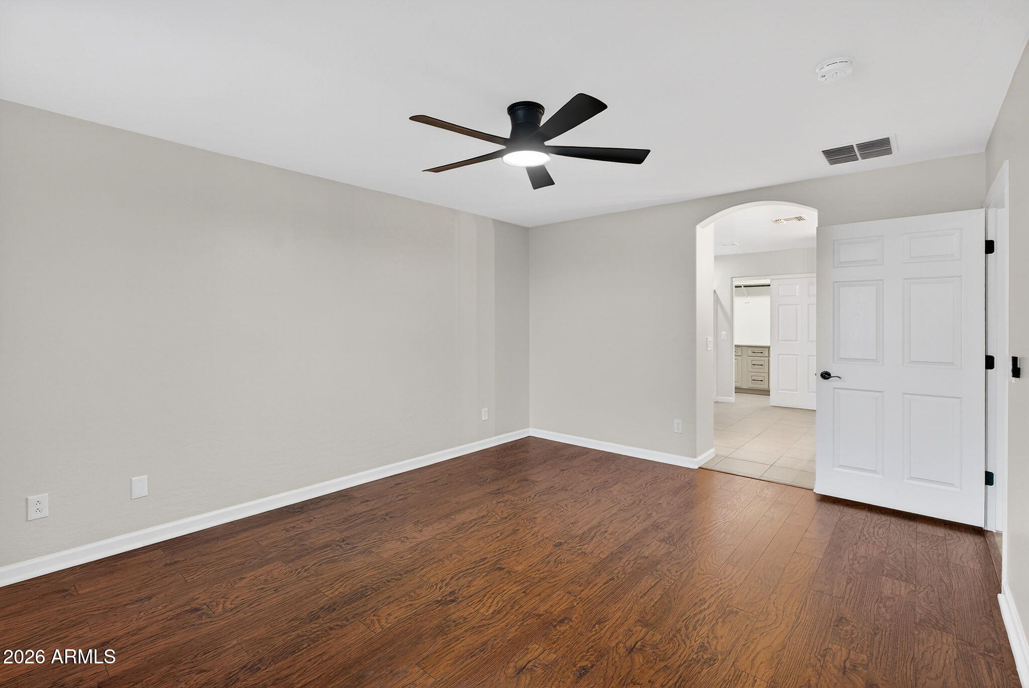 1815 South 174th Avenue Goodyear, AZ 85338 - Photo 32 of 57 an empty room with wooden floor a ceiling fan and windows