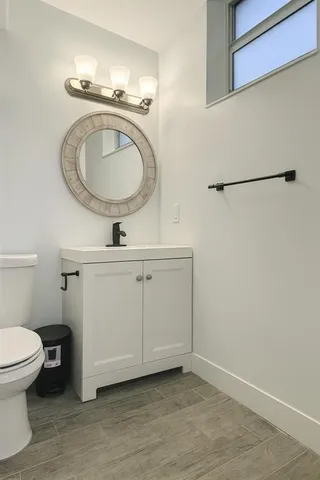 a bathroom with a sink a toilet mirror and vanity