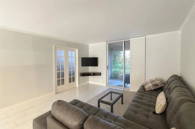 a living room with furniture a flat screen tv and a large window