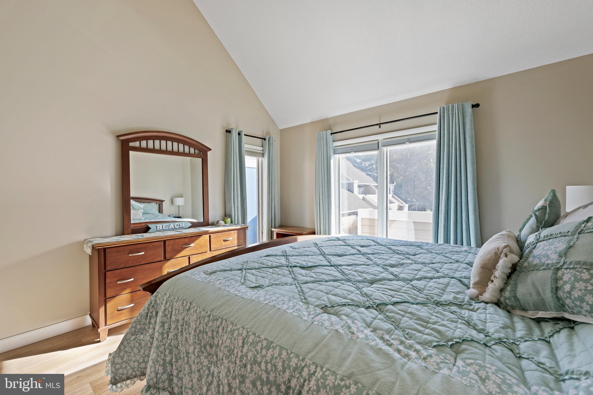 20852 Spring Lake Drive, Unit 405 Rehoboth Beach, DE 19971 - Photo 12 of 45 a bedroom with a bed and a dresser with mirror