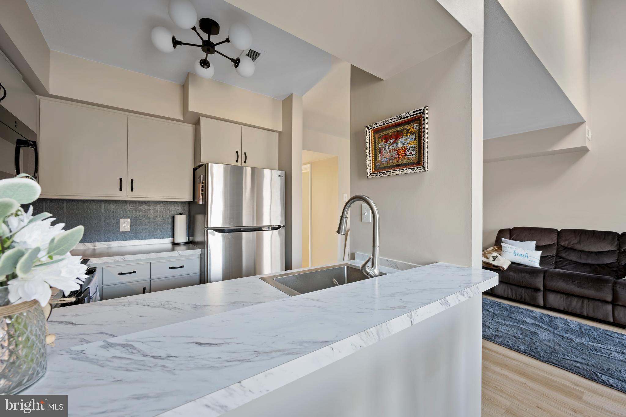 20852 Spring Lake Drive, Unit 405 Rehoboth Beach, DE 19971 - Photo 3 of 45 a kitchen with stainless steel appliances kitchen island granite countertop a refrigerator a stove and a sink with wooden floor
