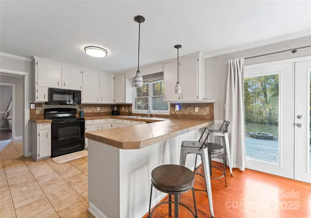 a kitchen with stainless steel appliances granite countertop a stove a sink a oven a refrigerator a stove and white cabinets with wooden floor