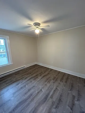 an empty room with wooden floor fan and windows