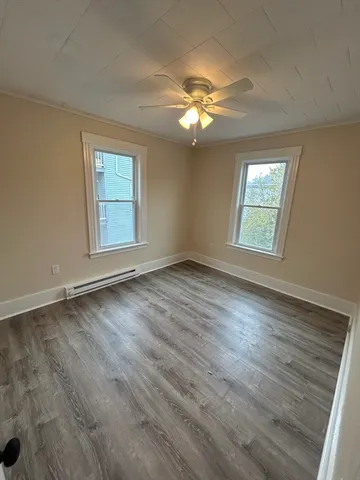 a view of an empty room with a window and wooden floor