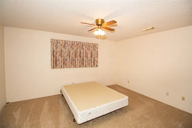 an empty room with a ceiling fan and a window