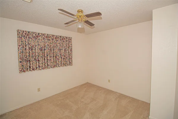 an empty room with a ceiling fan and a window