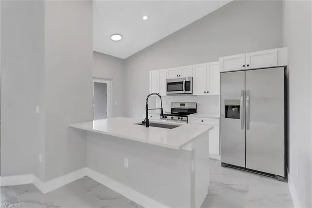 a kitchen with stainless steel appliances a refrigerator stove and white cabinets