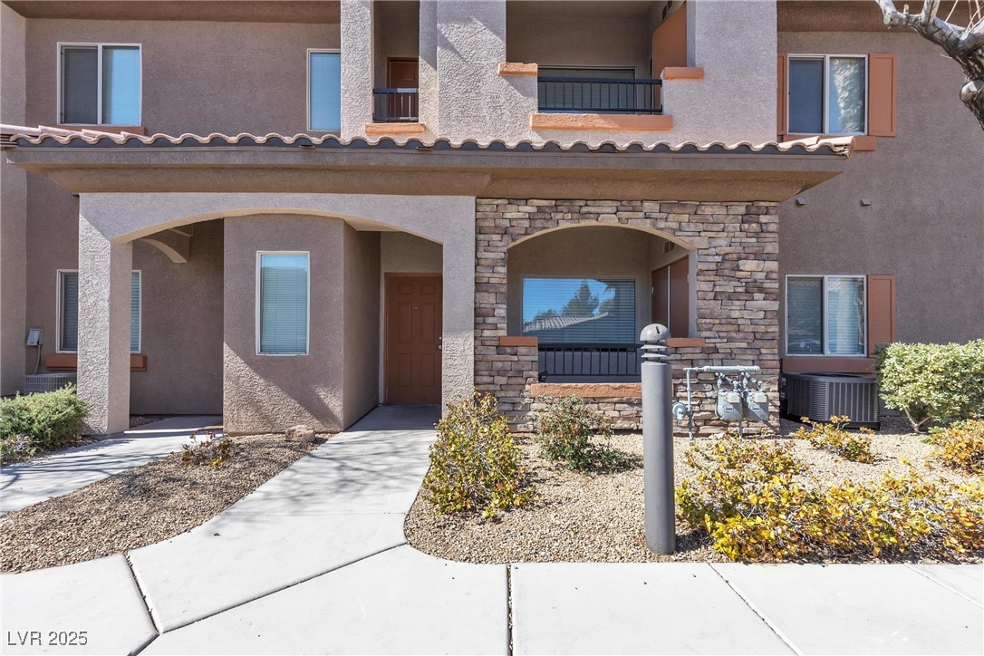 7701 West Robindale Road, Unit 102 Las Vegas, NV 89113 - Photo 1 of 28 View of exterior entry featuring stone siding, central air condition unit, and stucco siding