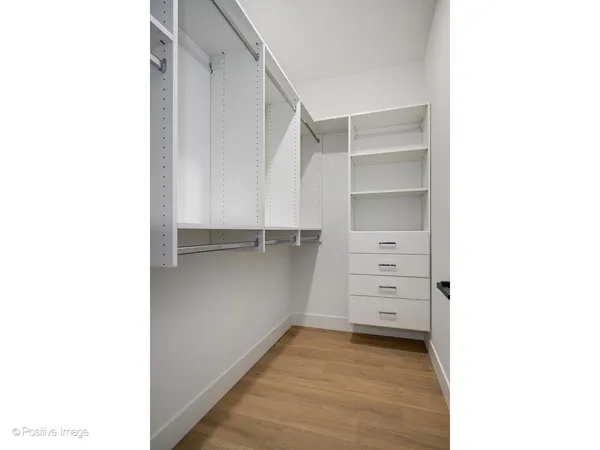 a view of an empty walk in closet with wooden floor