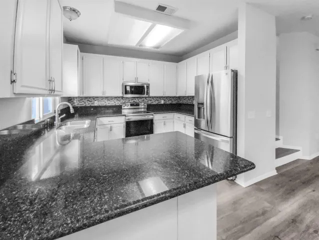 a kitchen with stainless steel appliances granite countertop a sink refrigerator and cabinets
