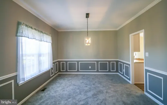 a view of an empty room with chandelier fan and a window