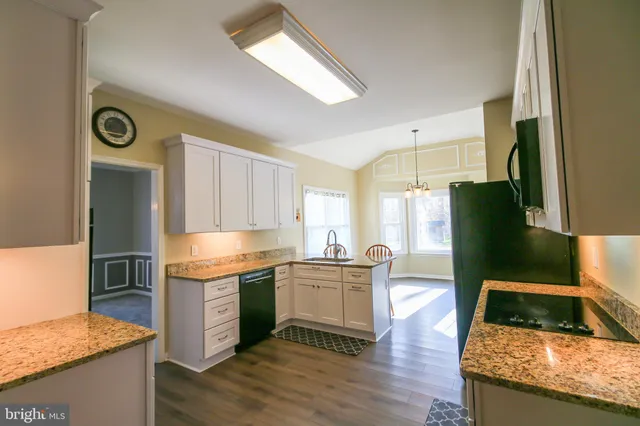 a kitchen with granite countertop a stove a sink and a refrigerator