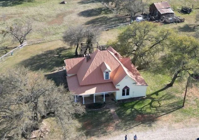 a aerial view of a house with a yard and large tree