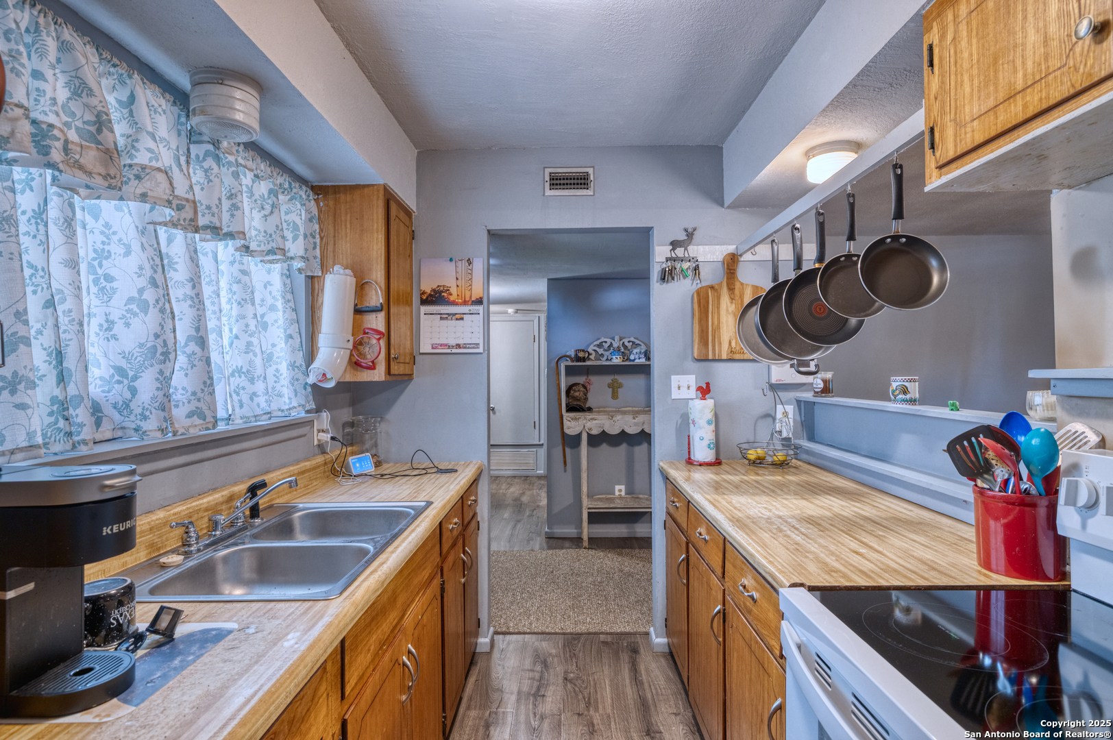 121 Rio Grande Street Uvalde, TX 78801 - Photo 9 of 29 a kitchen that has a sink a stove and a wooden cabinets