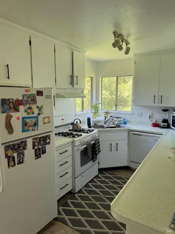 a kitchen with a stove a sink a window and cabinets