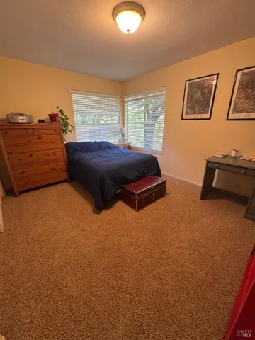 a bedroom with a bed and dresser with wooden floor