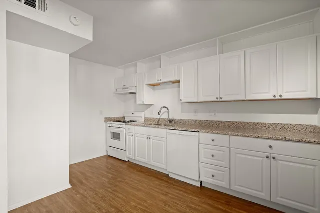 a kitchen with granite countertop white cabinets and white appliances