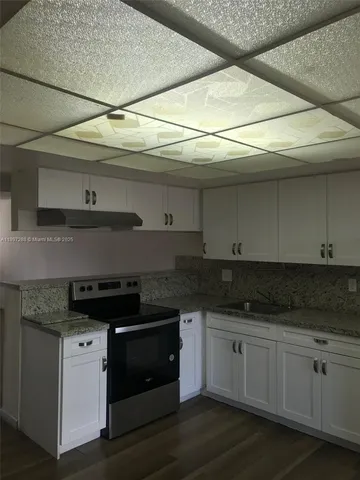 a kitchen with granite countertop white cabinets and black appliances