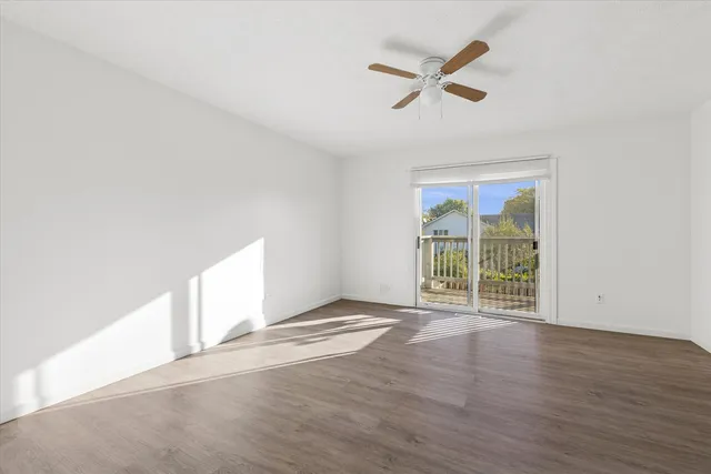 an empty room with wooden floor fan and windows
