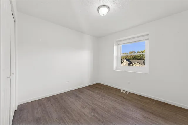 an empty room with wooden floor and window