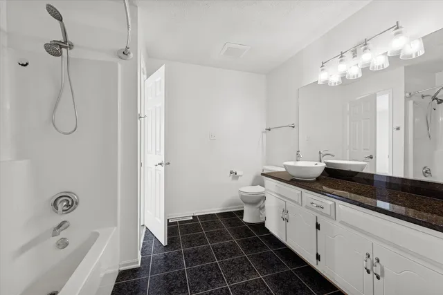 a spacious bathroom with a granite countertop sink a toilet mirror and shower