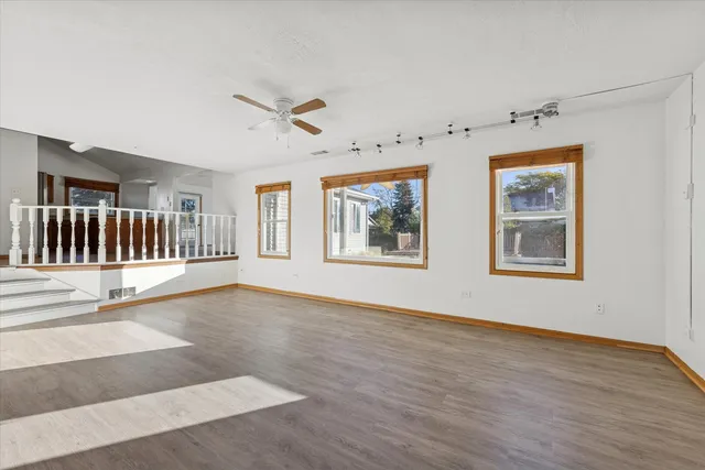 a view of an empty room with a window and wooden floor