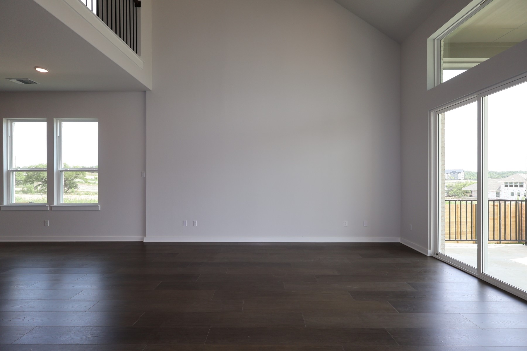 436 Leaning Rock Road Georgetown, TX 78628 - Photo 3 of 22 an empty room with wooden floor and windows with curtains