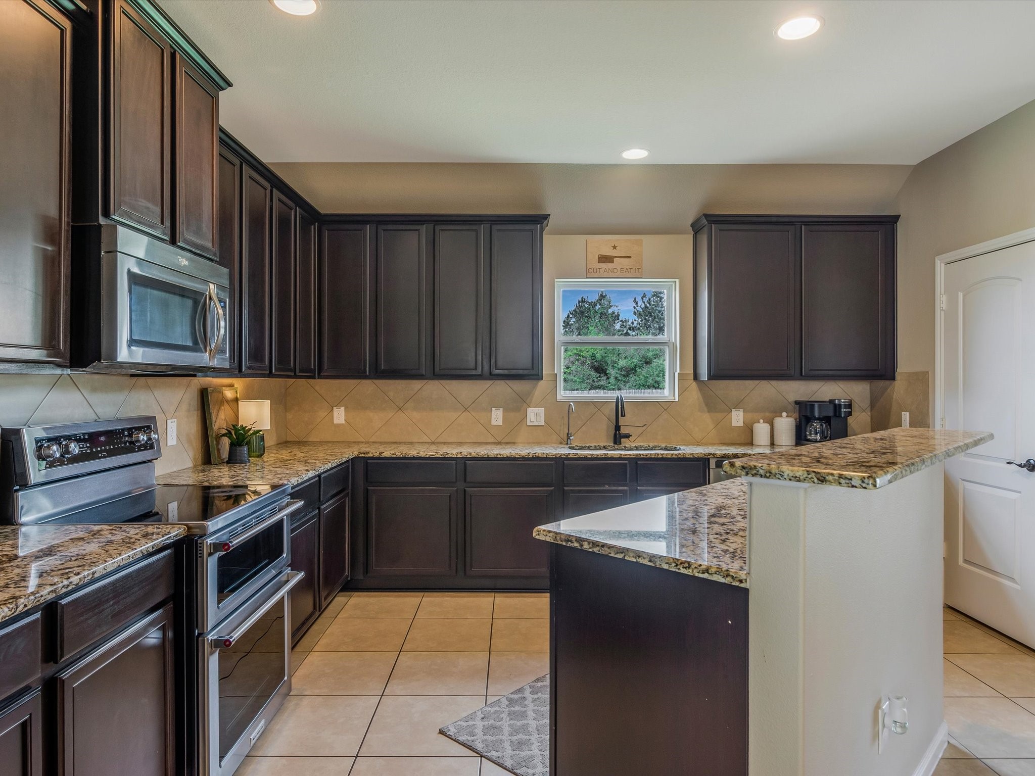 18746 Encinal Trail Magnolia, TX 77355 - Photo 15 of 35 a kitchen with a sink a stove top oven a refrigerator and cabinets