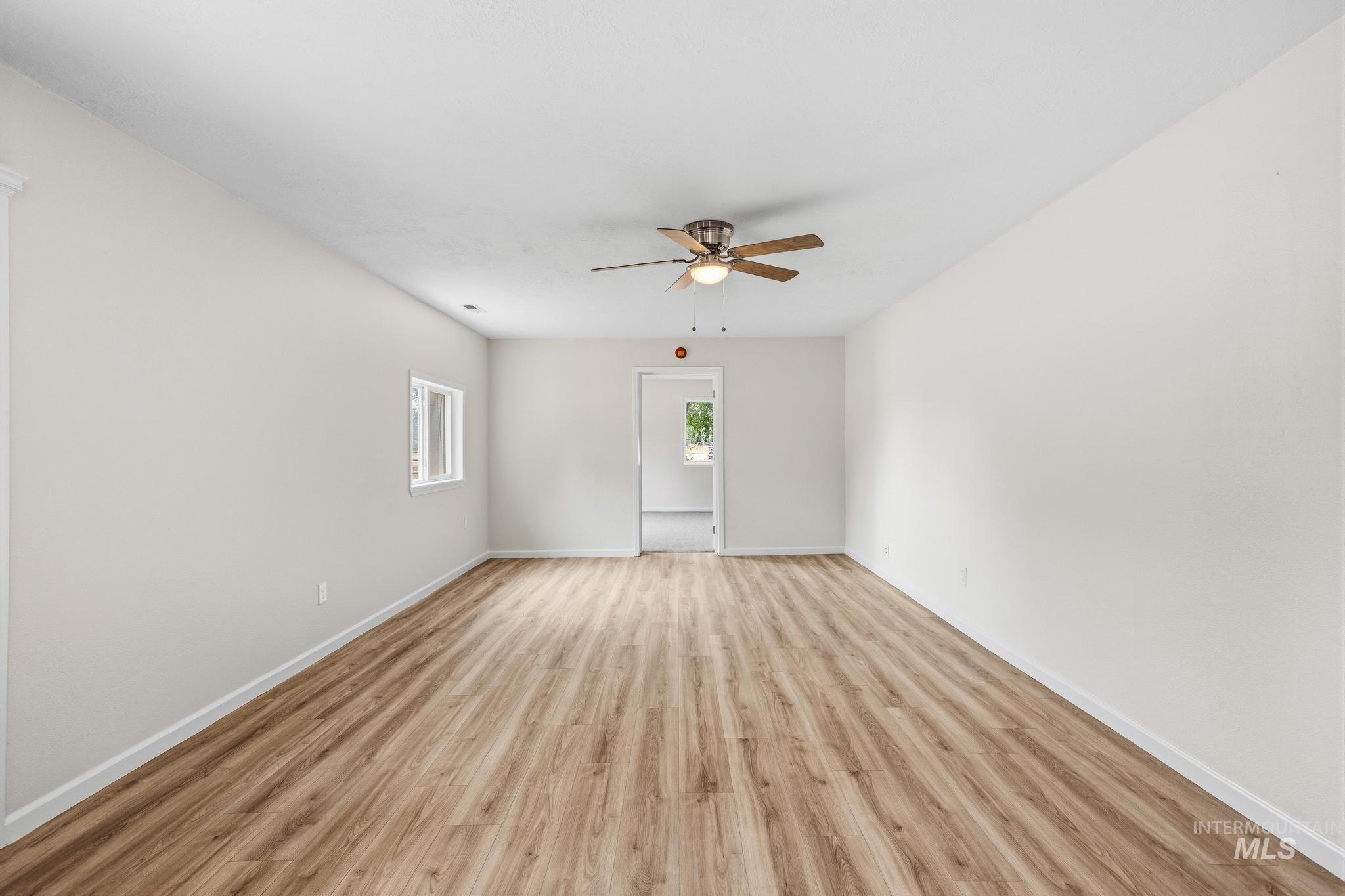 14666 Willis Road Caldwell, ID 83607 - Photo 13 of 50 Spacious room featuring wood-finish flooring, light-colored walls, a ceiling fan, and white trim