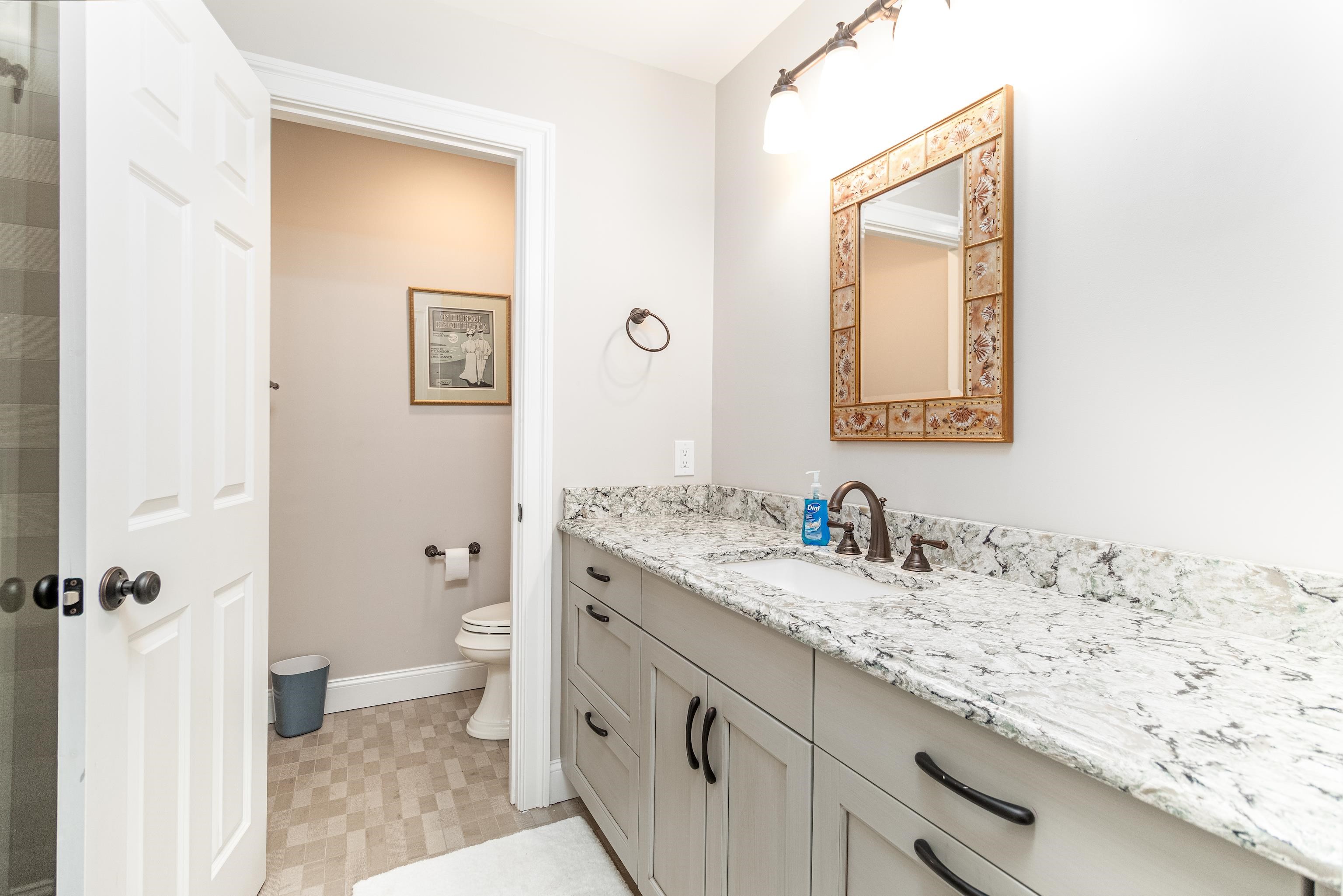178 37th Street Avalon, NJ 08202 - Photo 9 of 26 a bathroom with a granite countertop sink a toilet and a mirror