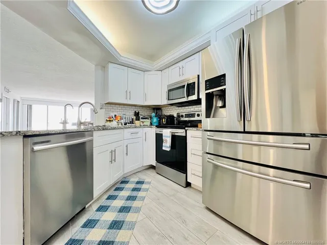 a kitchen with stainless steel appliances a dining table chairs and wooden floor