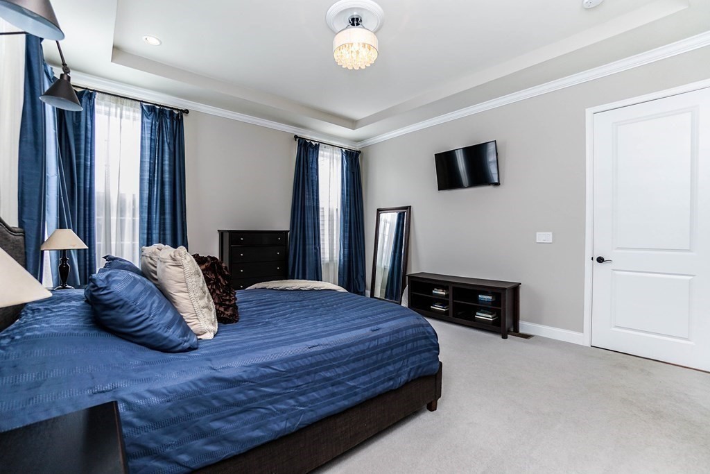 27 Pine Tree Drive, Unit 27 Methuen, MA 01844 - Photo 14 of 39 a bedroom with a bed a dresser and potted plants with wooden floor